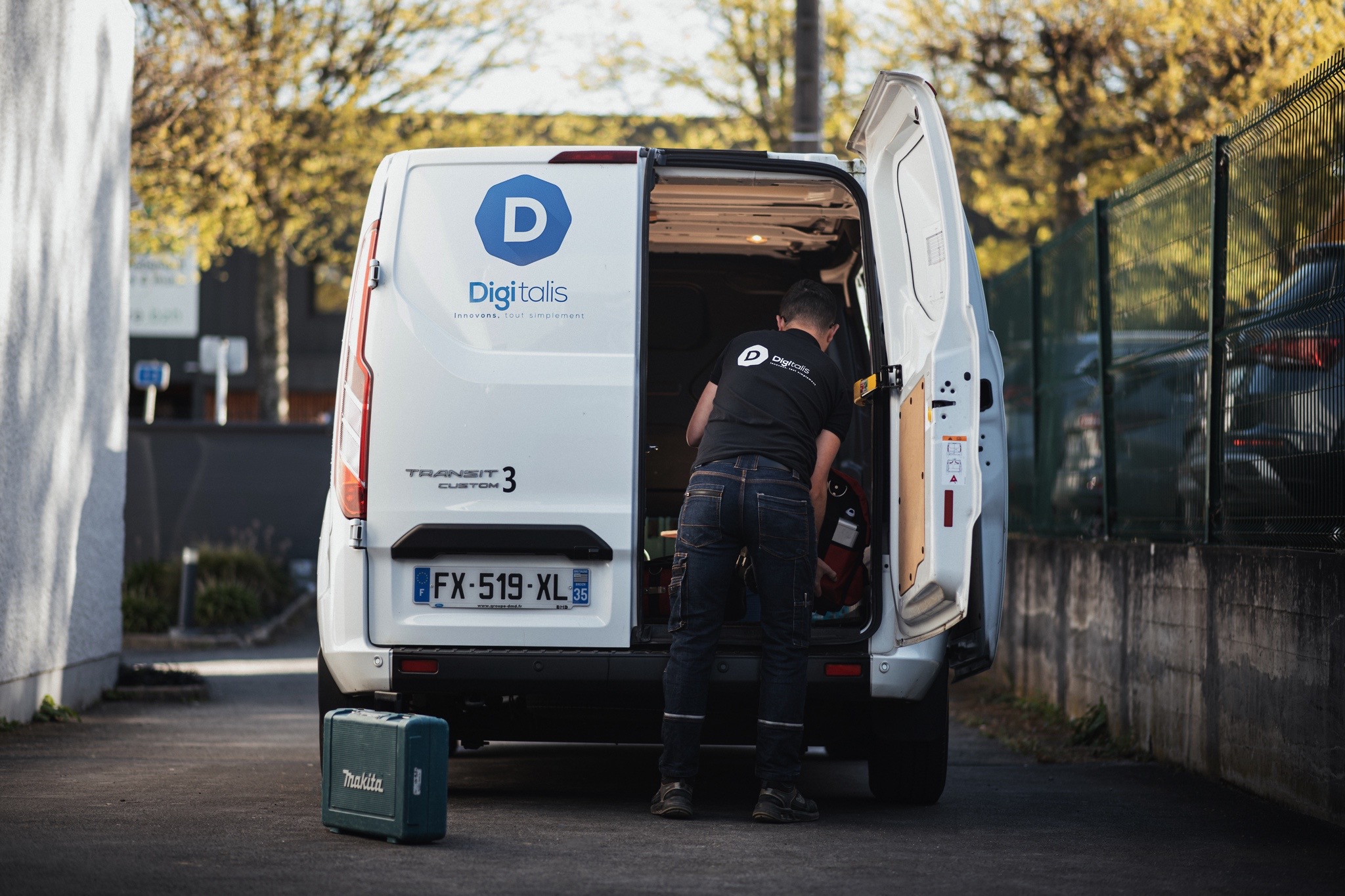 Homme chargeant des outils dans un fourgon blanc.